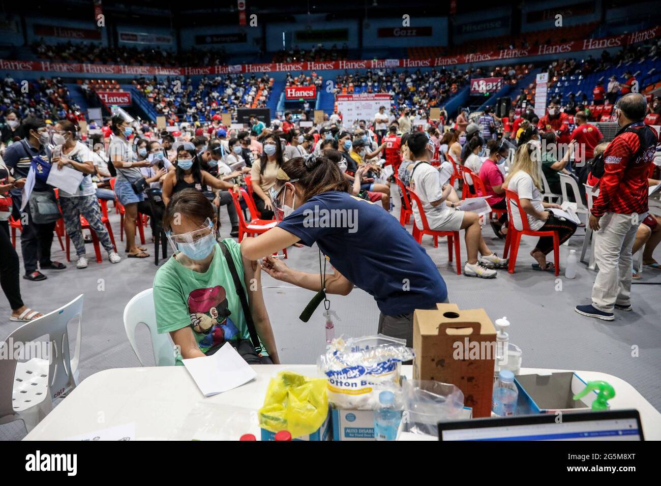 Ein Gesundheitsmitarbeiter impft einen Patienten mit dem COVID-19 Pfizer-BioNTech-Impfstoff in einem Sportstadion ein, das zu einer temporären Impfstelle in San Juan City, Metro Manila, Philippinen, wurde. Stockfoto