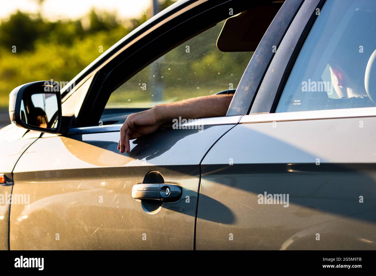 Fahrer hält Hand an der Autotür mit geöffnetem Fenster und wartet im Verkehrskonzept aus nächster Nähe. Bukarest, Rumänien, 2021 Stockfoto
