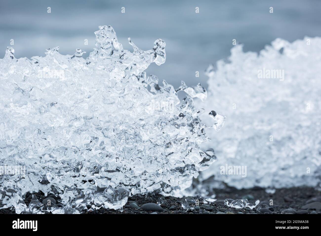 Eine Nahaufnahme von strukturierten Eisbergbrocken, die auf schwarzem Sand am Diamond Beach in Island schmelzen. Stockfoto