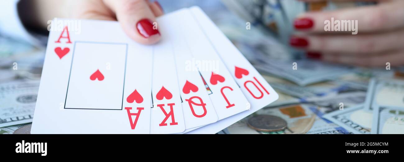 Frau hält Dollarscheine und spielt Karten in ihren Händen Stockfoto