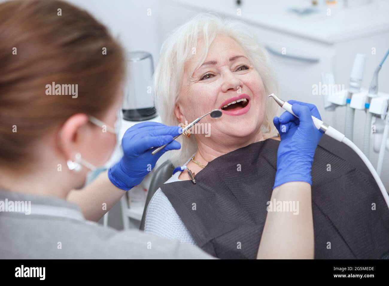 Glückliche ältere Frau bekommt Zahnbehandlung durch einen professionellen Zahnarzt Stockfoto