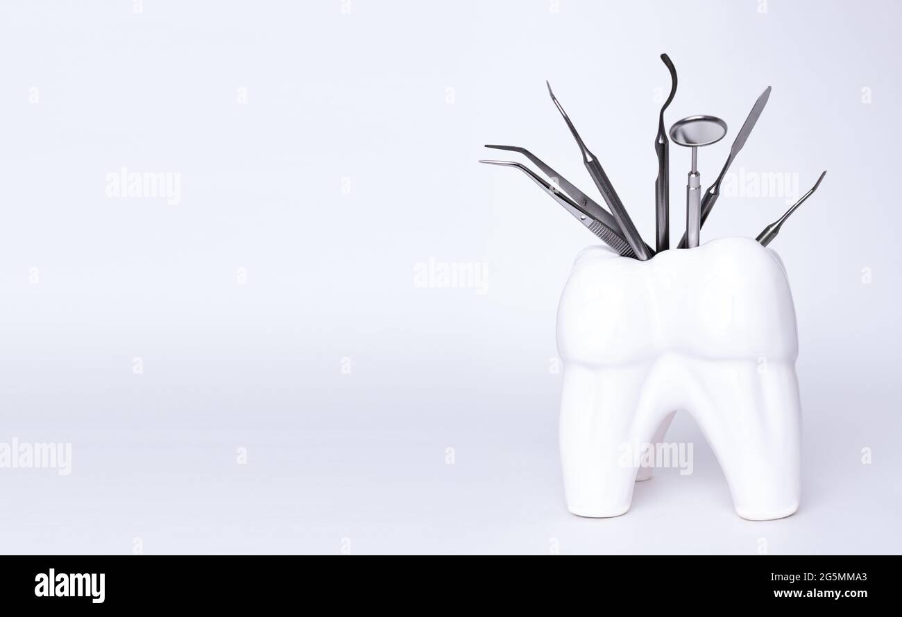 Zahnärztliche professionelle Stahlwerkzeuge in zahnförmigem Halter auf grauem Hintergrund. Set von medizinischen Geräten aus Metall für die Zahnpflege. Sichelsonde Stockfoto
