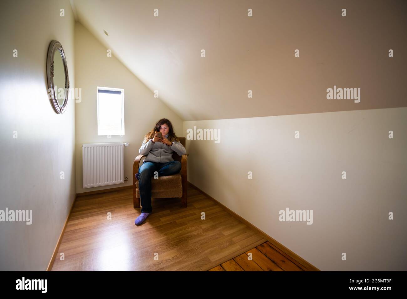Europäische Loft-Zimmer Schlafzimmer im Gästehaus mit Frau am Fenster am Telefon in Haus Innenhaus Wohnung im Hostel Hotel sitzen Stockfoto