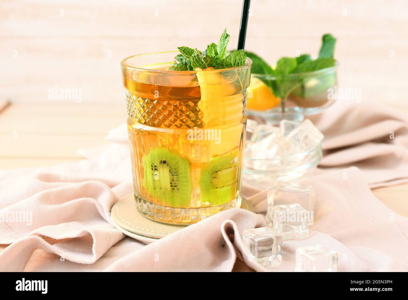 Glas leckeren Eistee mit Apfel und Kiwi auf farbigem Holzhintergrund Stockfoto