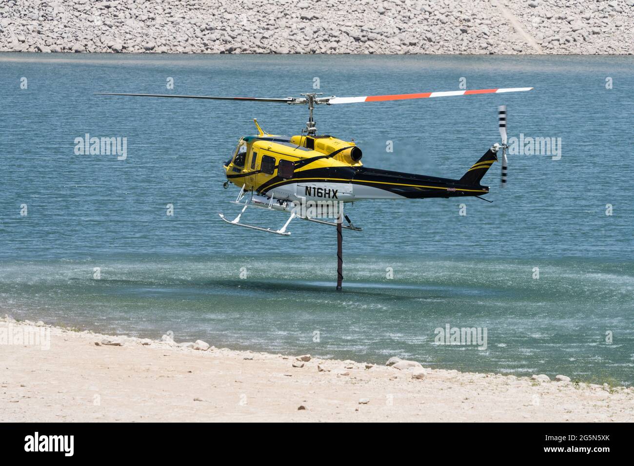 Ein Bell 205-A1 Feuerwehrhubschrauber füllt sich mit Wasser aus einem See zur Feuerunterdrückung und Brandbekämpfung aus der Luft in Utah. Stockfoto