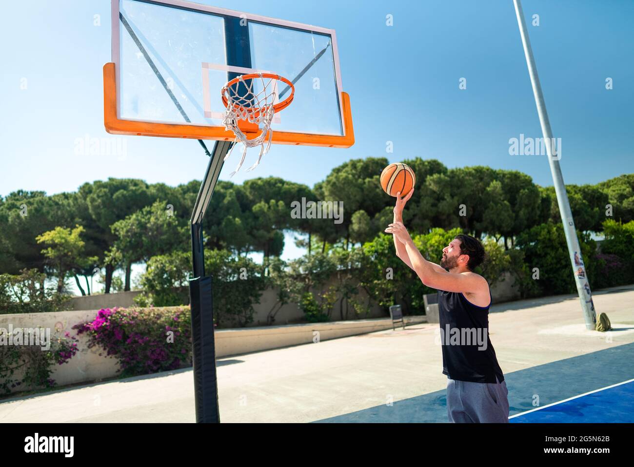 Männliche Sportler spielen Basketball werfen den Ball auf dem Spielplatz, dabei erfolgreich Slam Dunk Blick von hinten. Präzisionsschuss Stockfoto