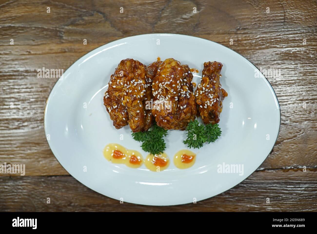 Hochwinkelansicht von knusprigem Honig-Sesam-Huhn mit einer klebrig-asiatischen Sauce. Stockfoto