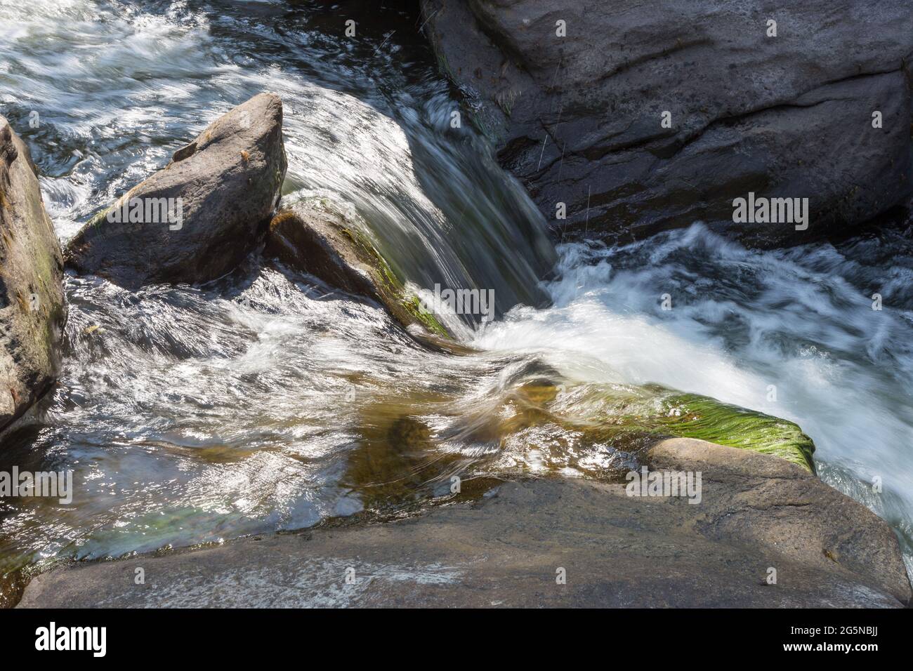 Bergwasser fließt zwischen Steinen Stockfoto