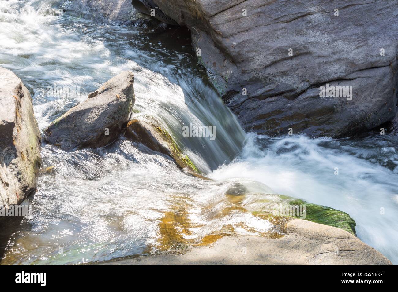 Bergwasser fließt zwischen Steinen Stockfoto
