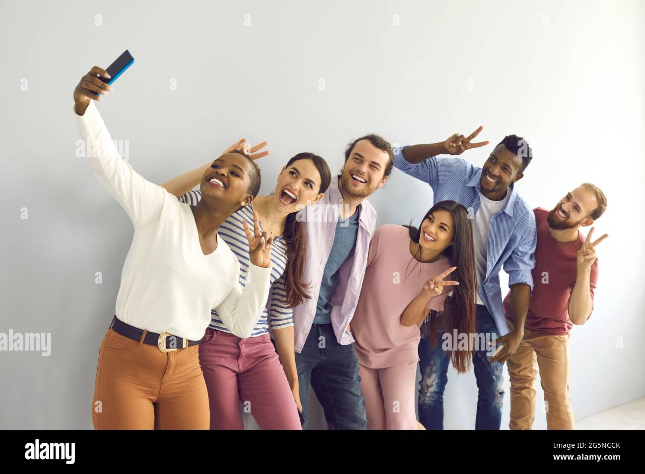 Gruppe lächelnder multinationaler Studenten oder Freunde, die V-Zeichen-Gesten zeigen und Selfie machen. Stockfoto
