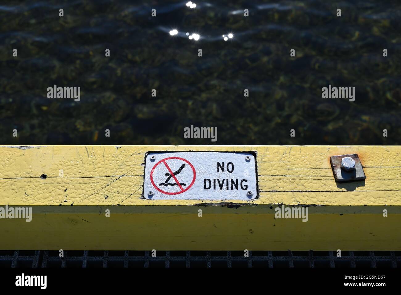 Ein nasses No-Diving-Schild an einem Pier oder Steg, das vor der Gefahr durch den flachen Wasserbalg warnt Stockfoto