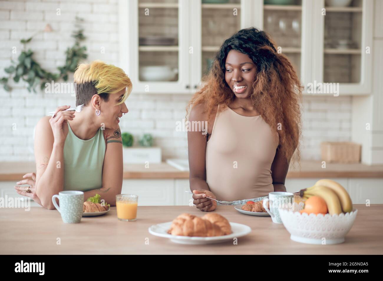 Zwei Freundinnen, die morgens in der Küche gefrühstückt haben Stockfoto