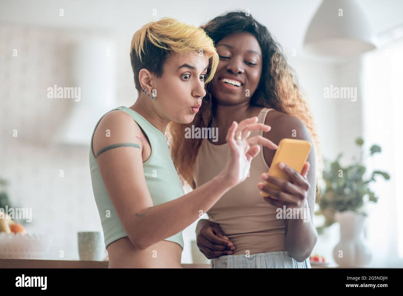 Überrascht Frau Blick auf Smartphone und enthusiastische Freundin Stockfoto