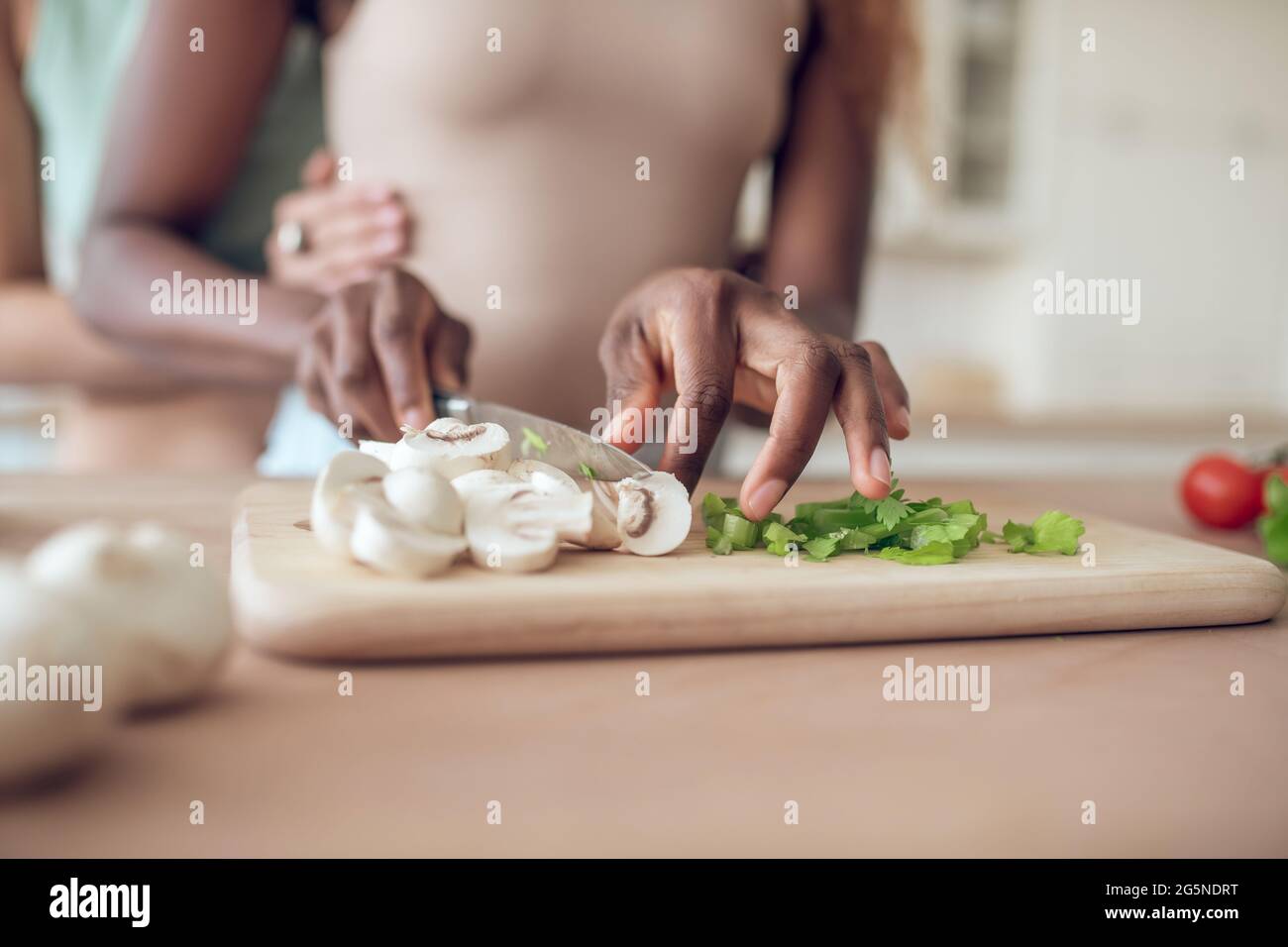 Hände einer afroamerikanischen Frau schneiden frisches Gemüse Stockfoto