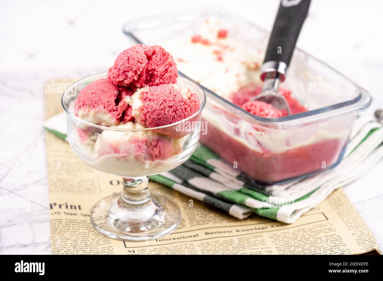 Erdbeerjoghurt in Glasschüssel, Eiskugeln, Behälter mit hausgemachten Eisgläsern Stockfoto