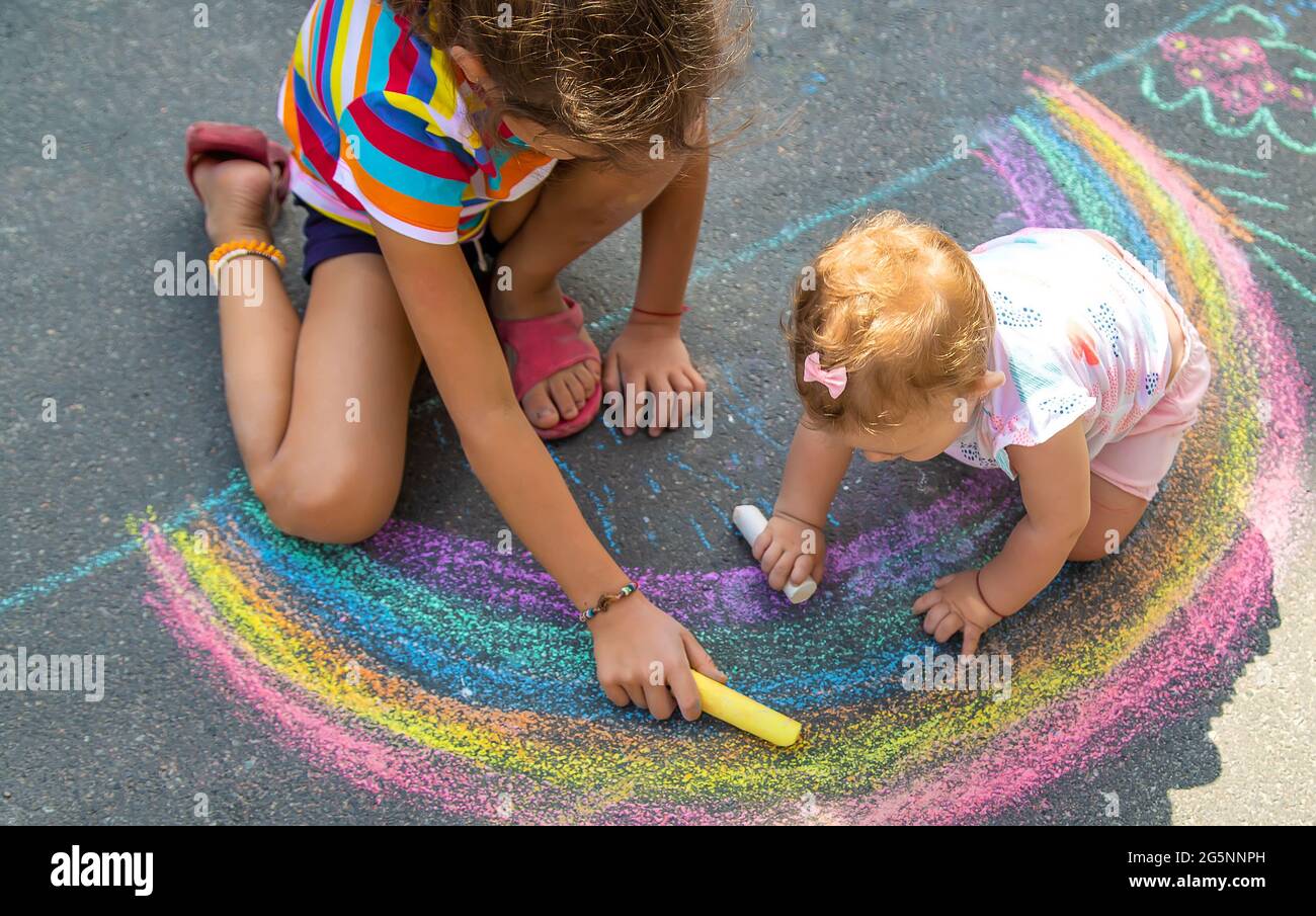 Das Kind Zeichnet Mit Kreide Ein Haus Und Einen Regenbogen Auf Den Das Kind Zeichnet Mit Kreide Ein Haus Und Einen Regenbogen Auf Den