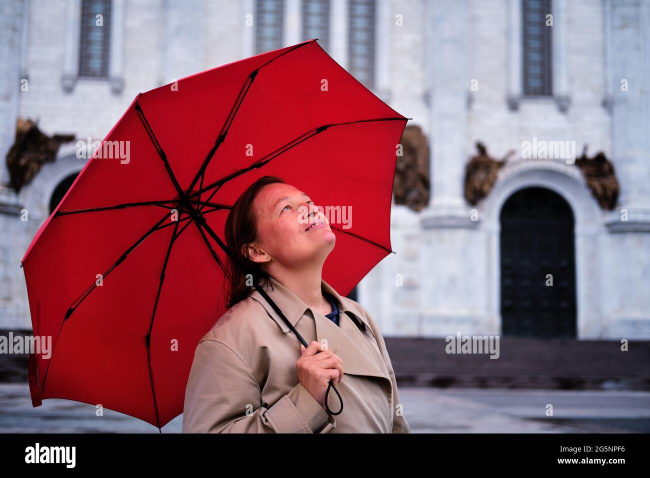 Glückliche Frau mit einem roten Regenschirm in einer orthodoxen Kirche Stockfoto