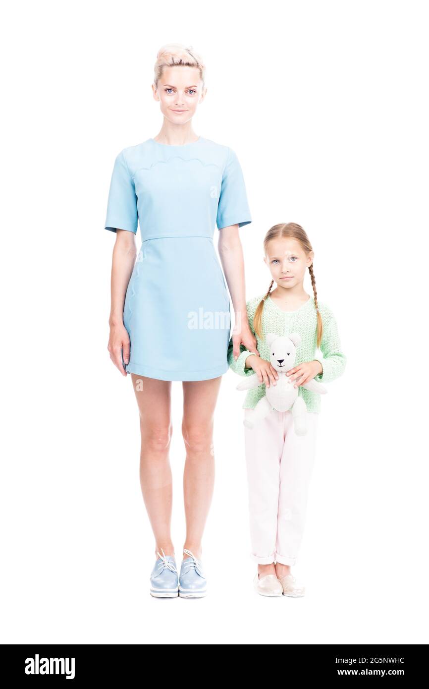 Vertikale Ganzlänge isoliert Aufnahme von schönen jungen erwachsenen Frau und ihre Tochter zusammen stehend Blick auf die Kamera, weißer Hintergrund Stockfoto