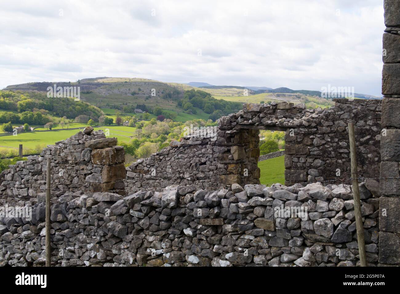 Altes Bauernhaus mit Trockenmauern mit sanften Hügeln und grünen Feldern in der Ferne in Yorkshire Dales Stockfoto
