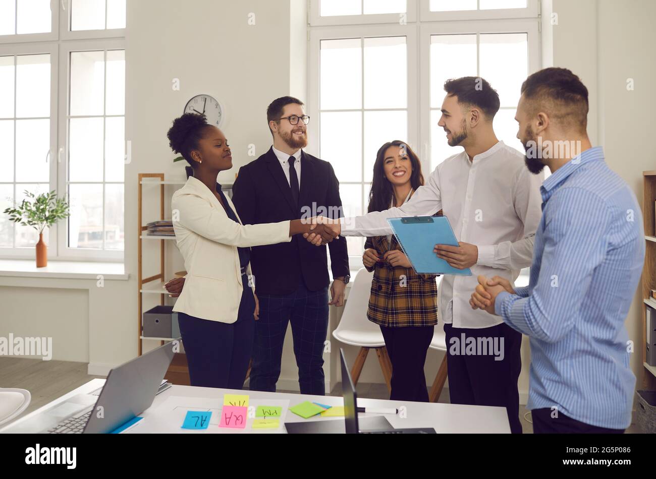 Kollegen aus dem Geschäftsteam schütteln sich die Hände, während sie im kreativen Büro arbeiten Stockfoto