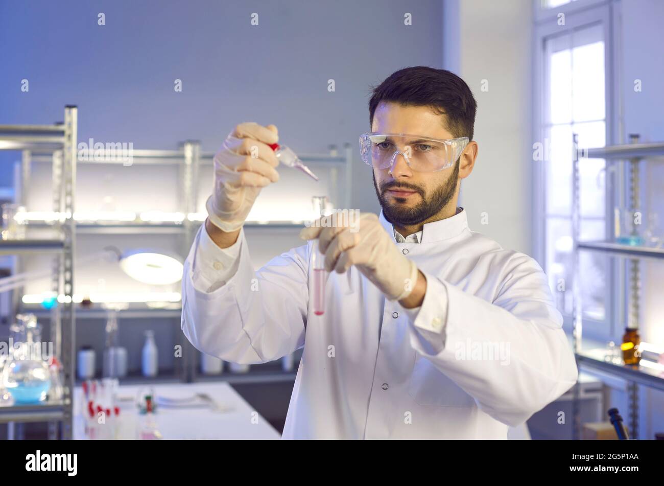 Forscher mit Schutzbrille und Handschuhen, die mit Reagenzgläsern arbeiten Stockfoto