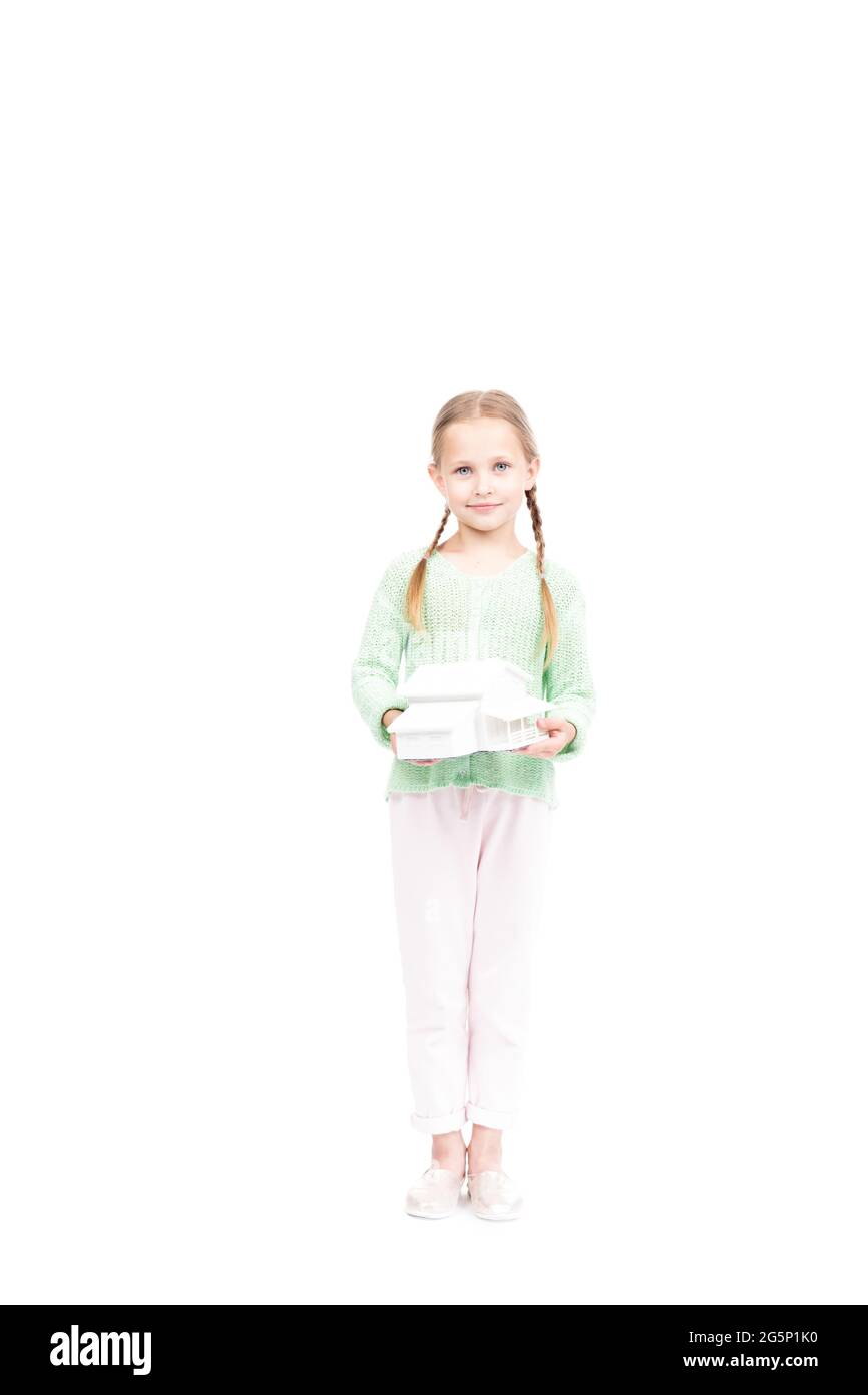 Studio Porträt von kleinen kaukasischen Mädchen trägt Freizeitkleidung halten Hausmodell in den Händen, weißer Hintergrund Stockfoto