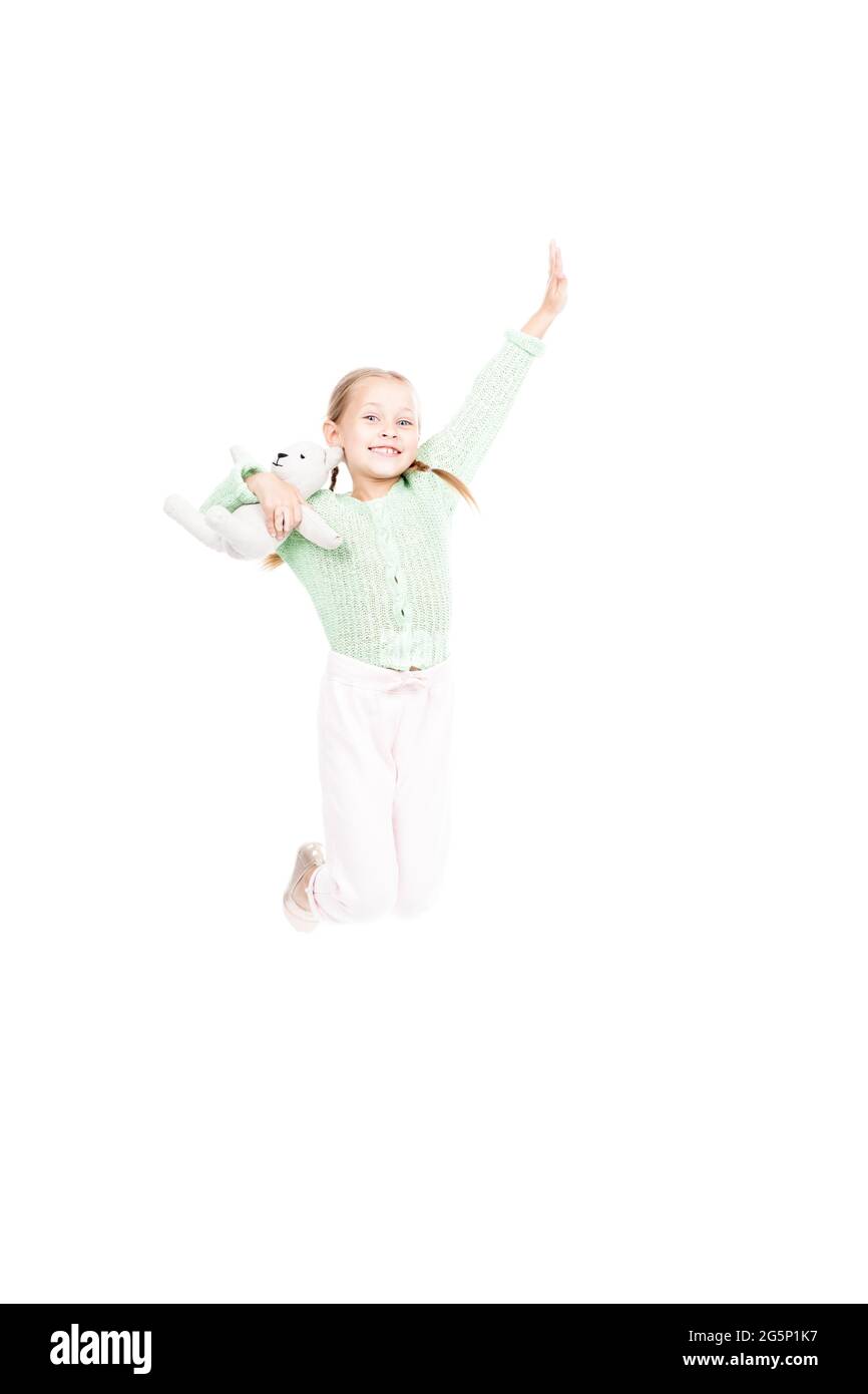 Vertikale volle Länge Studio Aufnahme von fröhlichen kaukasischen Mädchen halten Spielzeug springen lächelnd an der Kamera, weißer Hintergrund Stockfoto
