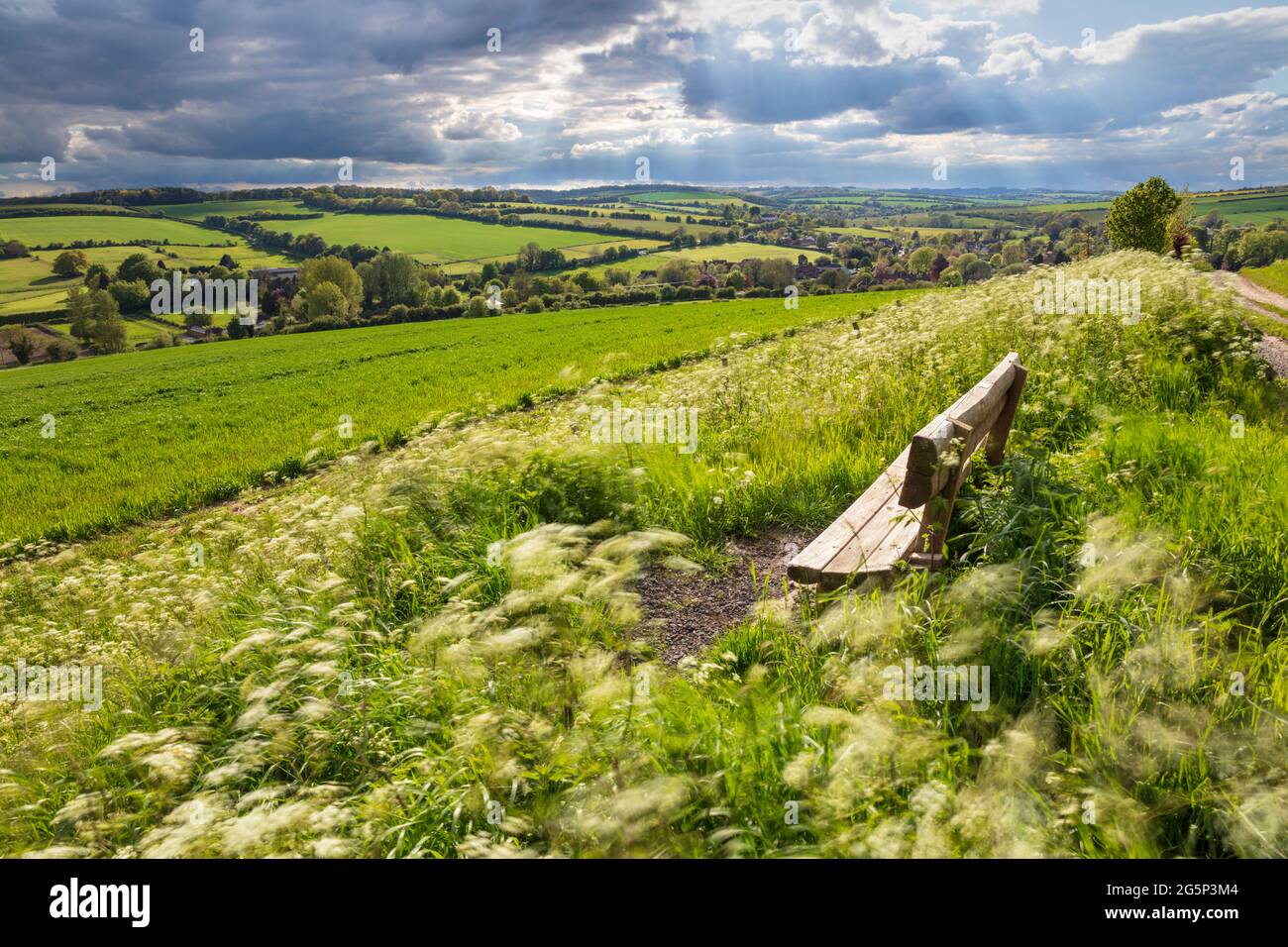 Holzbank mit Blick auf das Dorf East Garston und das Lambourn Valley im Frühjahr, East Garston, West-berkshire, England, Vereinigtes Königreich, Europa Stockfoto