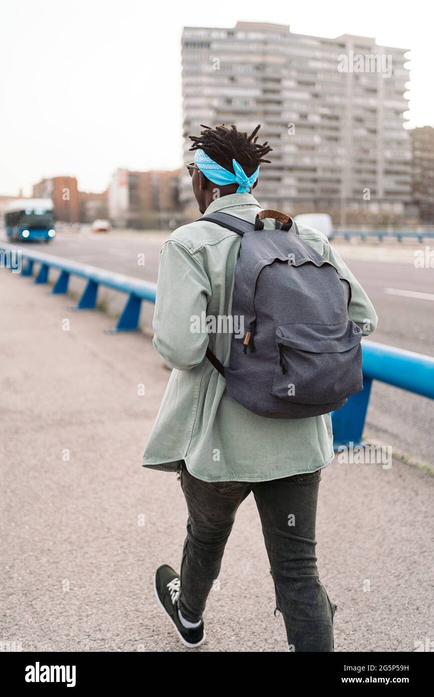 Unbekannter afrikanischer Mann, der Rucksack trägt und auf der Straße läuft. Stockfoto