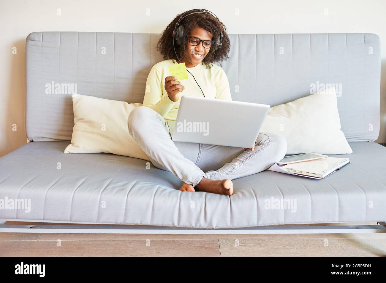 Afroamerikanische Frau auf dem Sofa am Laptop-Computer in den sozialen Medien während Video-Chat Stockfoto