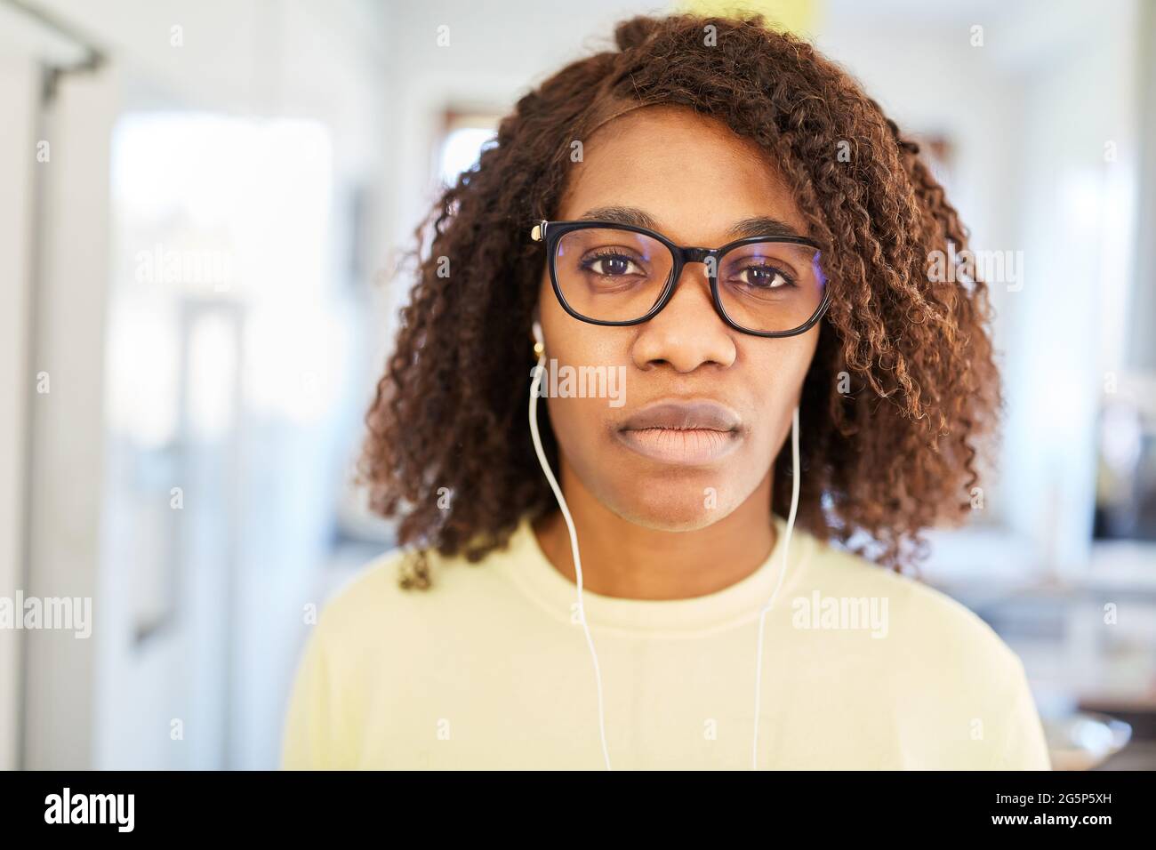 Afrikanische Frau als Studentin mit in-Ear-Kopfhörern während des E-Learning oder im Home Office Stockfoto