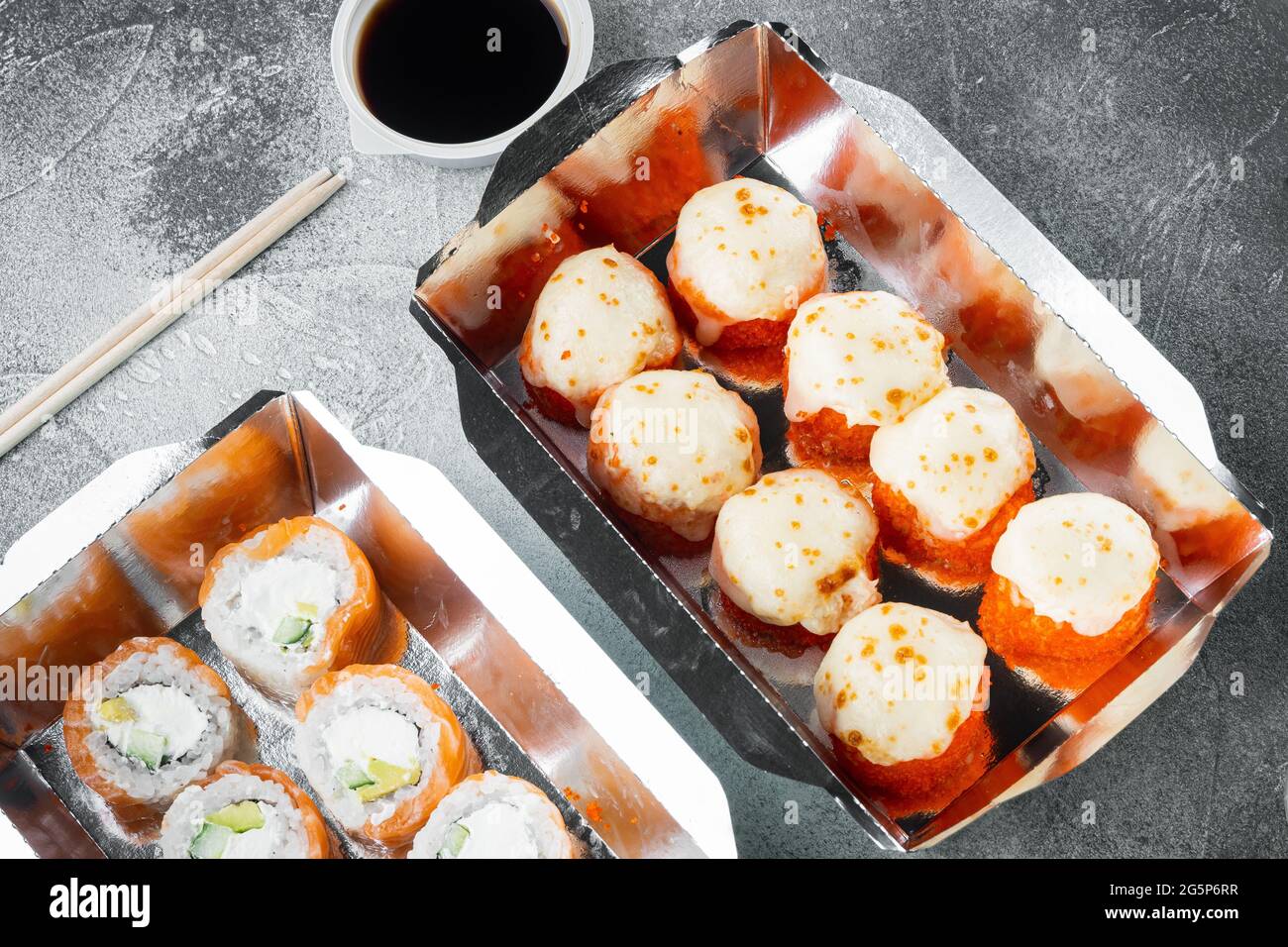 Japanisches Speisekonzept. Catering, verschiedene Arten von Sushi, philadelphia-Brötchen und gebackene Garnelenrollen auf grauem Stein Stockfoto