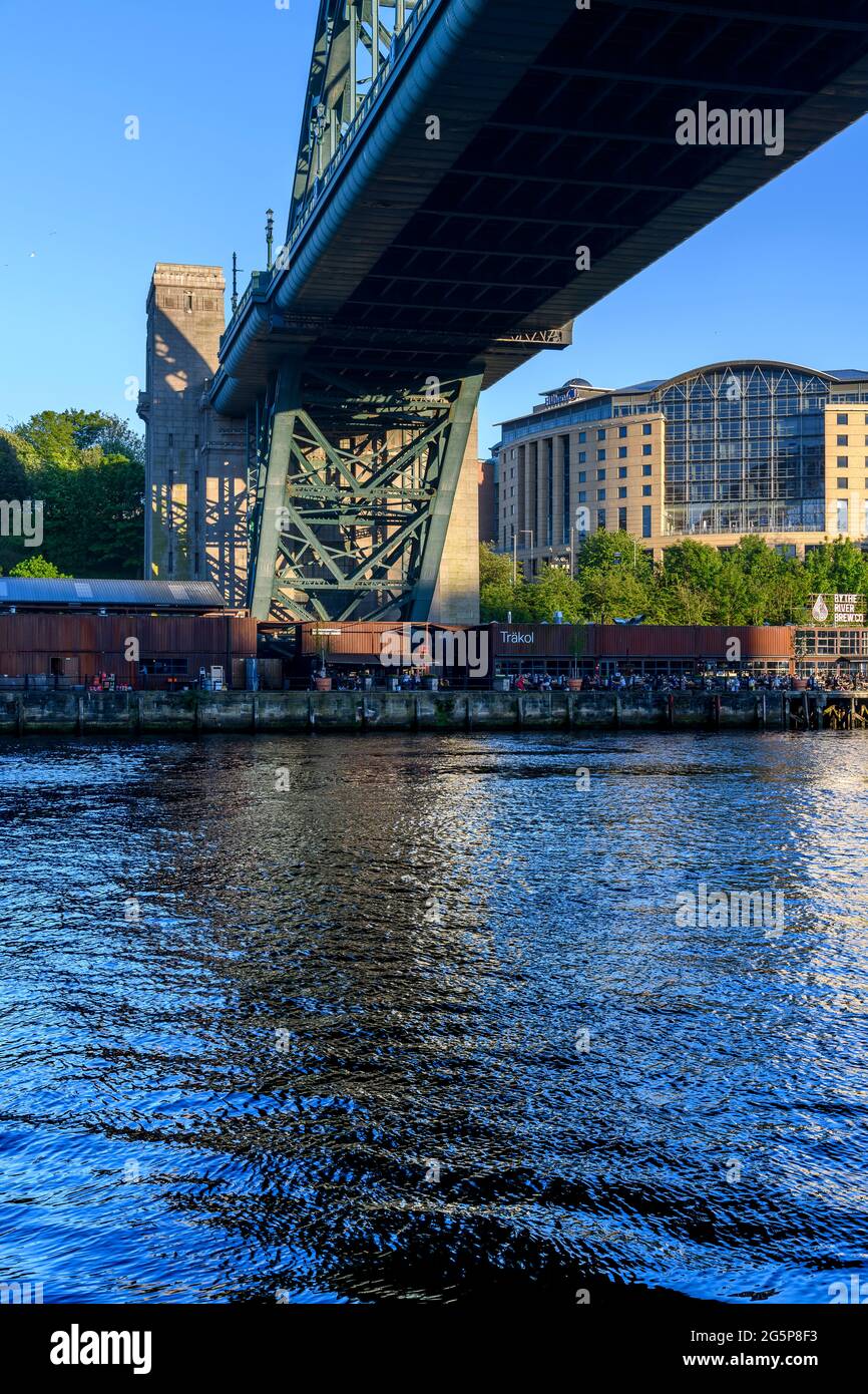 Die Gateshead-Seite des Flusses Tyne. Im Schatten der riesigen Tyne-Brücke. Das Gebiet darunter ist Träkol, ein Restaurant und eine Bar am Fluss. Stockfoto
