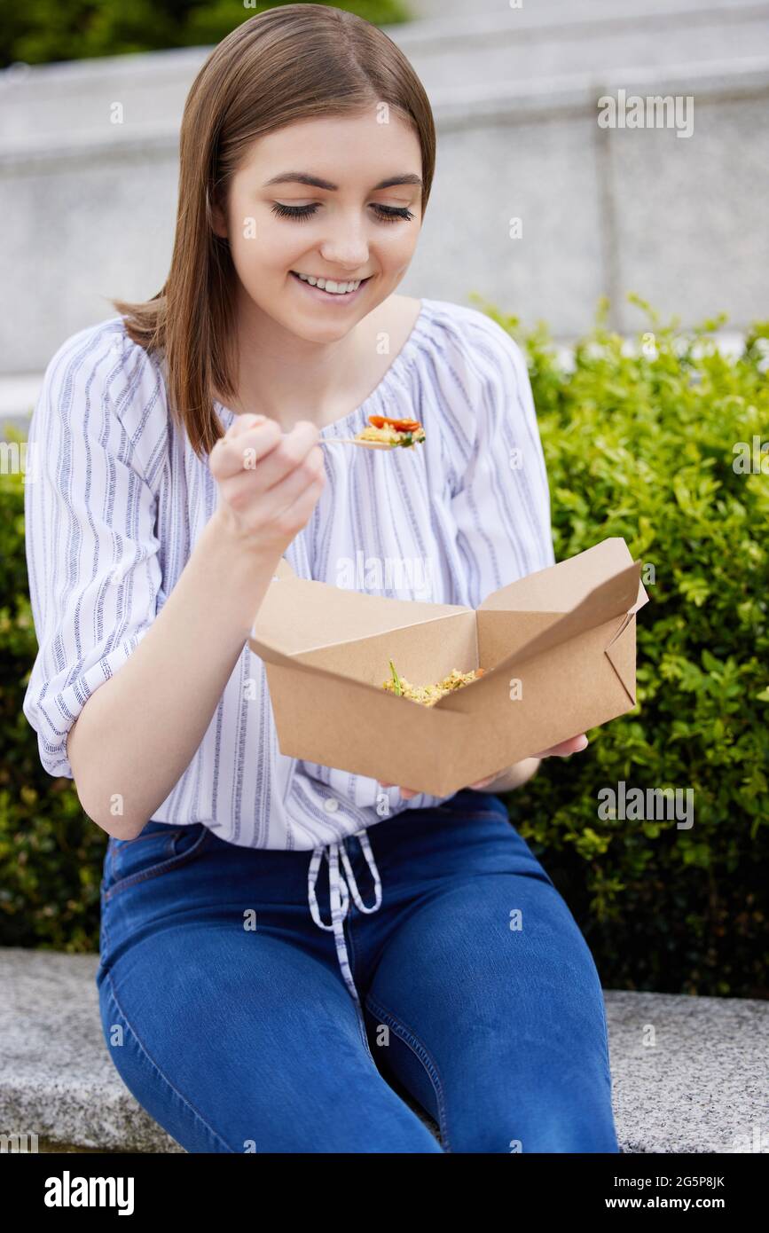 Frau, Die Gesund Vegan Oder Vegetarisch Isst Take Away Lunch Aus Recycelbarer Verpackung Mit Holzgabel Stockfoto