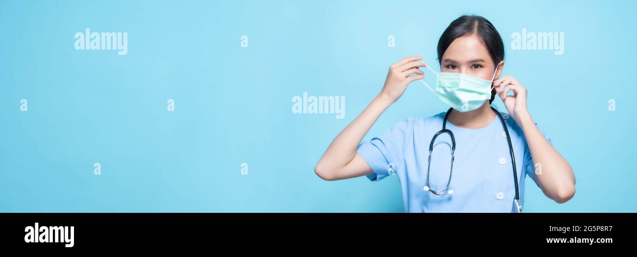 Porträt einer jungen asiatischen schönen Krankenschwester in blauer Uniform und trägt eine chirurgische Maske zum Schutz vor Covid19 oder Coronavirus-Krankheit isoliert in blu Stockfoto