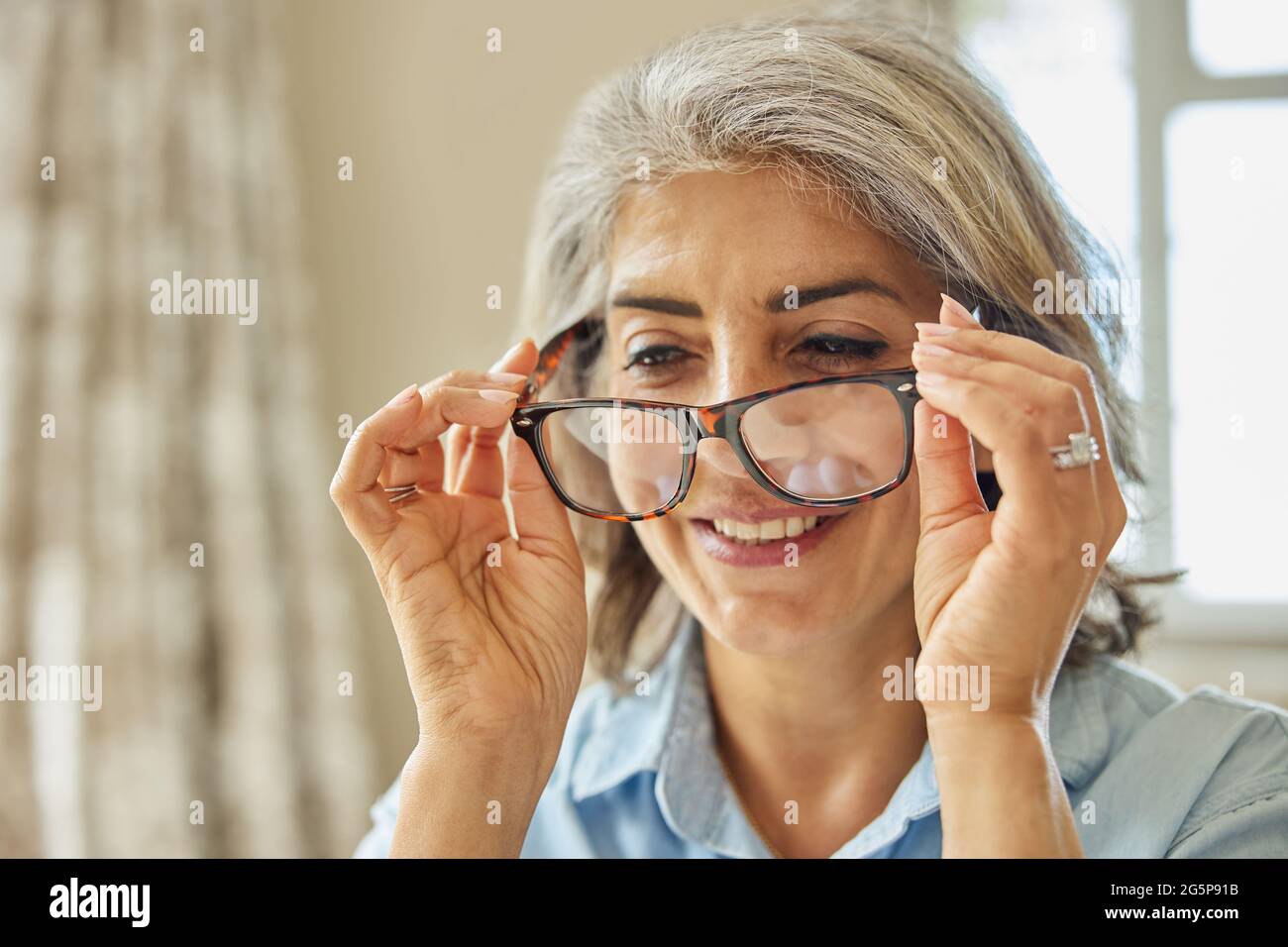 Lächelnde Reife Frau Versucht Auf Neue Gläser Zu Hause Stockfoto