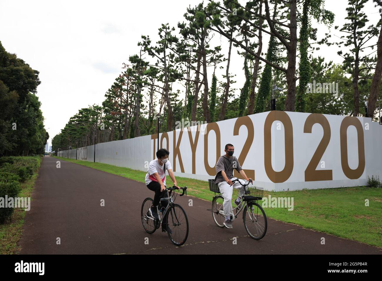 Tokio, Japan. Juni 2021. Männer auf dem Fahrrad fahren am Kasai Kanuslalom-Zentrum in Edogawa-Ku vorbei.25 Tage vor der Eröffnungsfeier der Olympischen Sommerspiele 2020 in Tokio befinden sich noch viele Sportstätten und Fanzonen im Bau. Kredit: SOPA Images Limited/Alamy Live Nachrichten Stockfoto