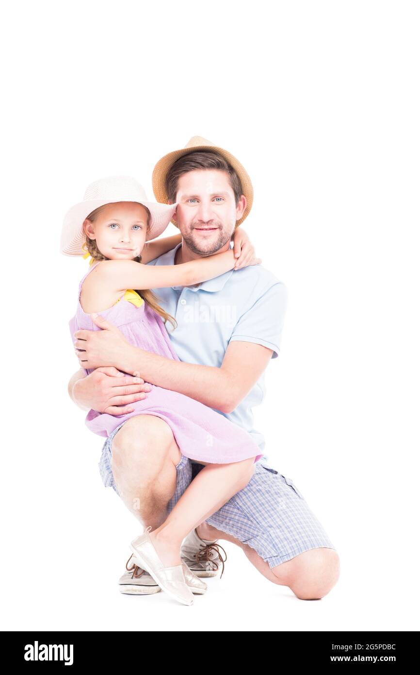 Vertikales Studioporträt von glücklichem Vater und ihrer niedlichen Tochter, die Sommeroutfits tragen, die sich umarmen und auf die Kamera schauen, weißer Hintergrund Stockfoto