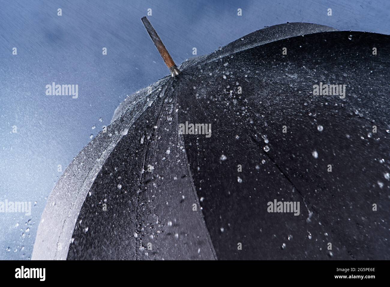 Schwarzer klassischer Regenschirm bei starkem Regen mit Wasser, das von der Regenschirmoberfläche abprallt. Stockfoto