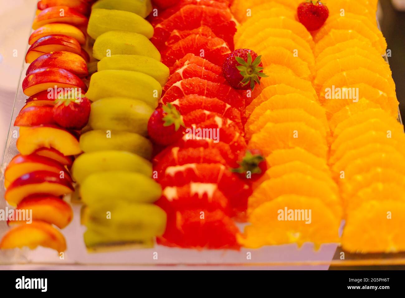 Orangenscheiben, Grapefruits, Kiwi, Pfirsiche und Erdbeeren auf einer großen Schüssel. Geschmack und Genuss. Erholung und Reisen. Konzept der gesunden lif Stockfoto