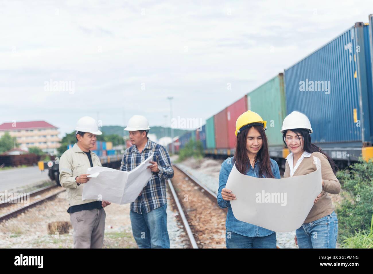 Bauingenieurteam mit Bauplan für das Projekt vor Ort, das in der Produktionsanlage für Eisenbahngleise arbeitet. Konzept Der Industrietechnik. Stockfoto