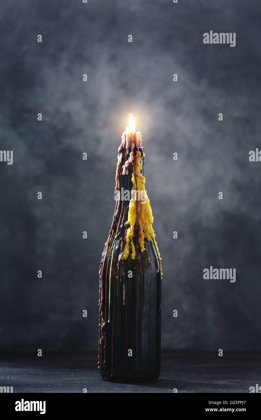 Brennende Kerze mit geschmolzenem Wachs in einer Flasche auf dunklem  Hintergrund, halloween-Dekoration mit mystischem Licht Stockfotografie -  Alamy