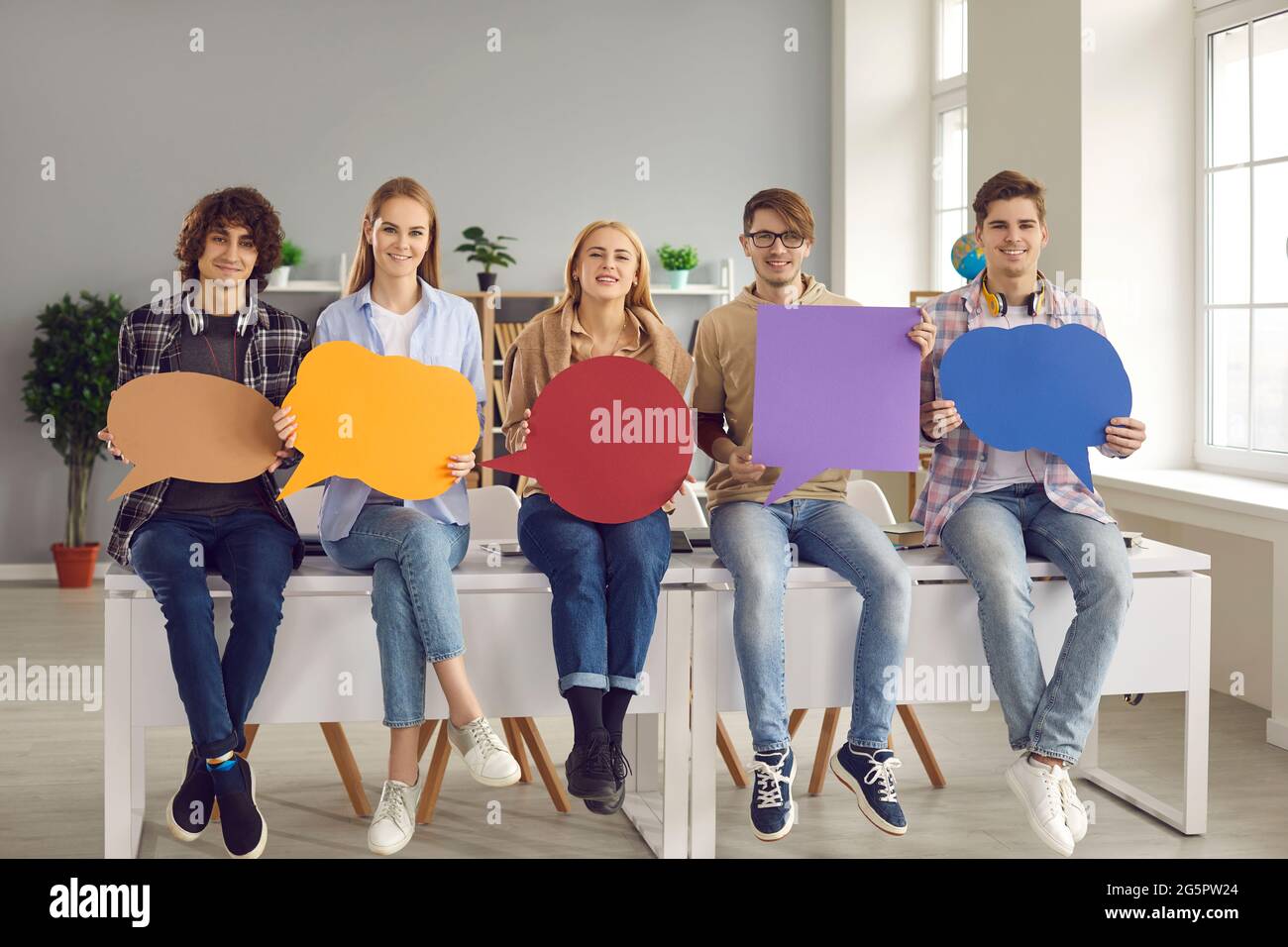 Junge Leute zeigen auf die leeren bunten Plakate mit Sprechblase mit Platz für Text. Stockfoto