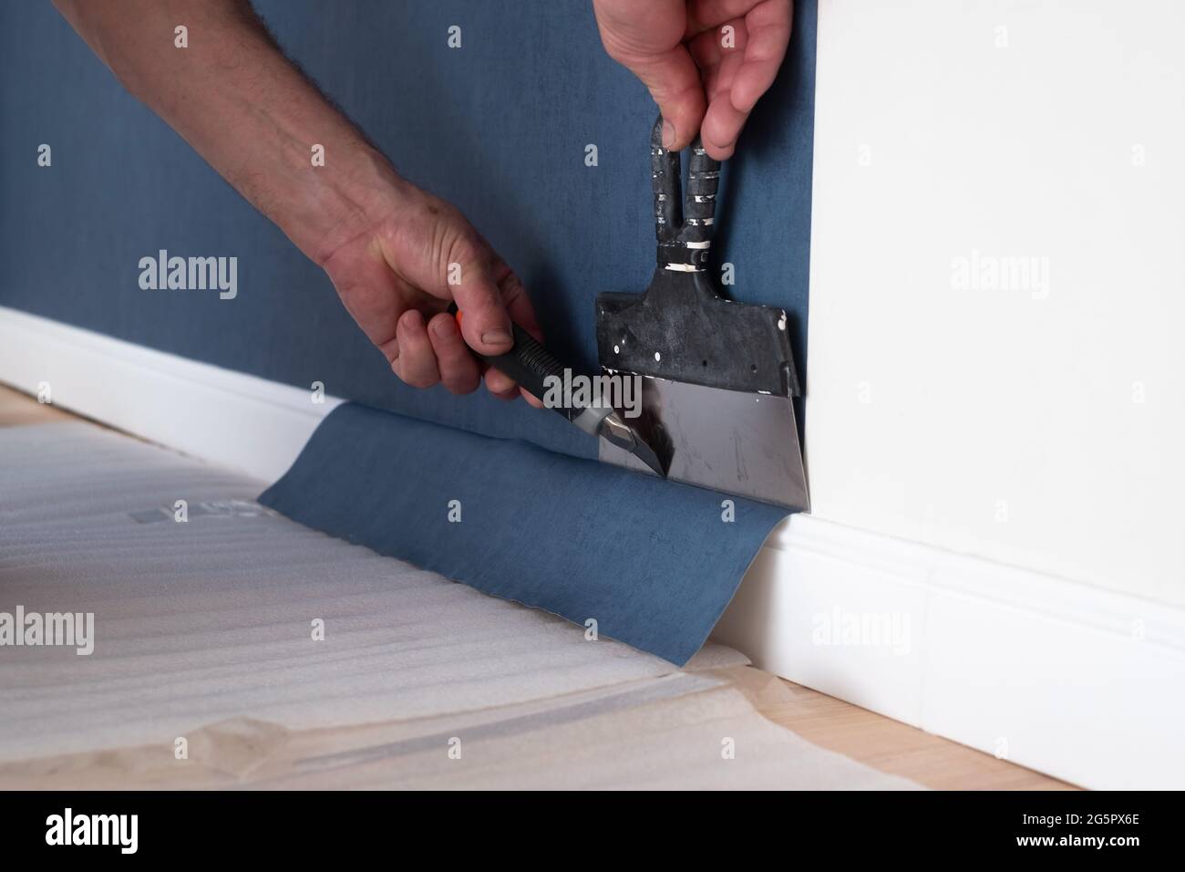 Mann schneidet Tapete. Instandsetzungsarbeiten Renovierung in der Wohnung. Stockfoto