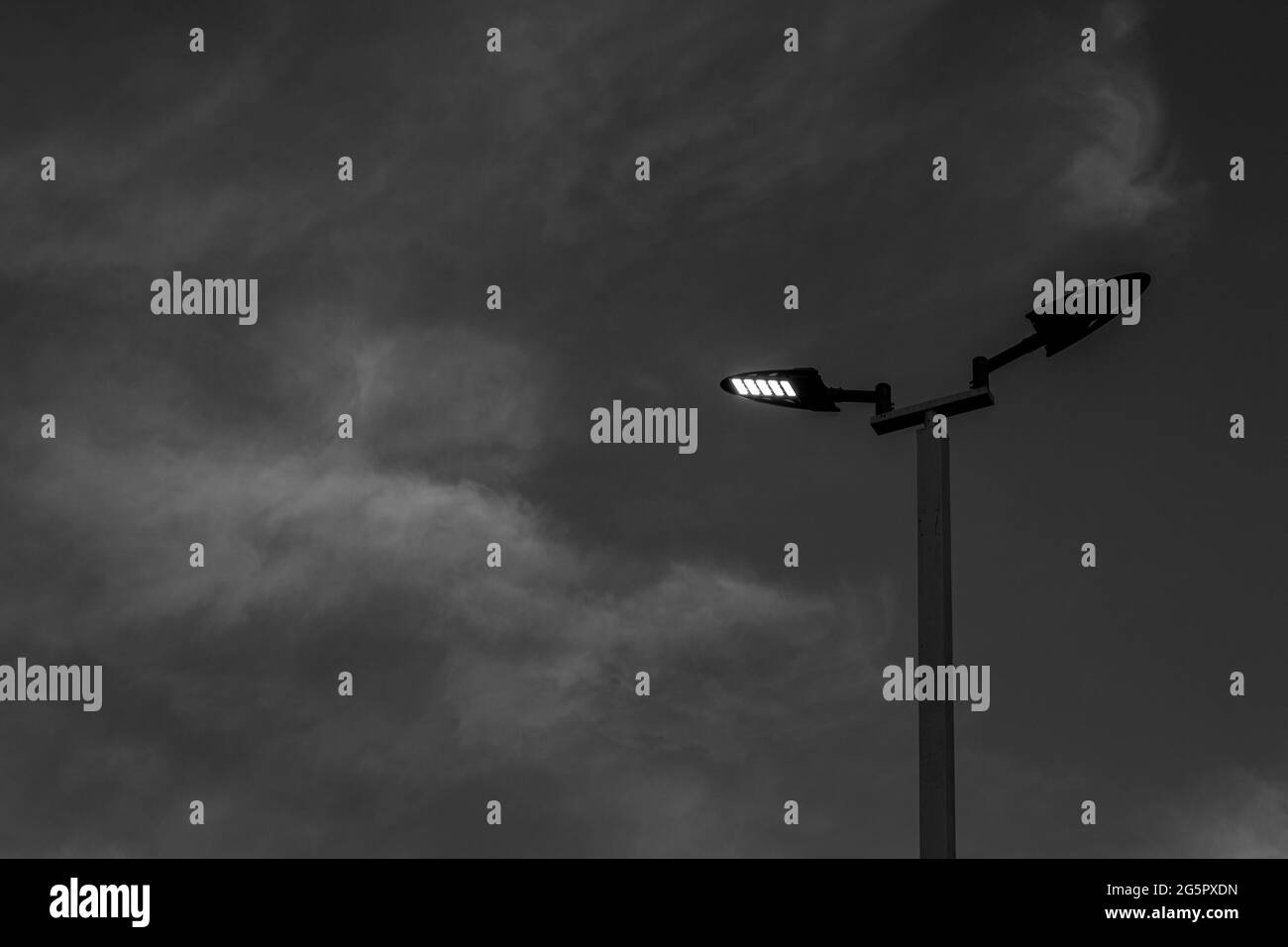 Straßenbeleuchtung unter dem Himmel am Abend in Schwarz-weiß-Tönen. Stockfoto