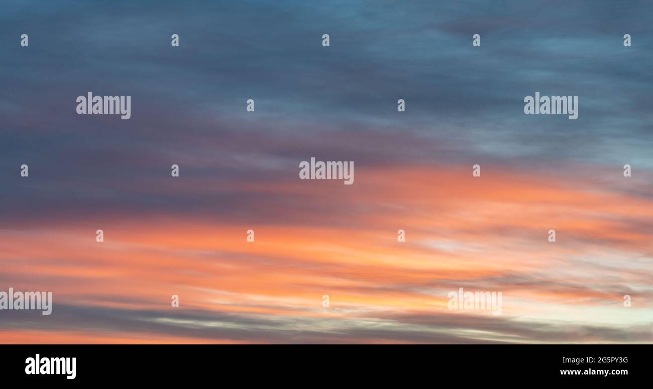 Farbenfrohes Foto des Himmels, das durch den rot-orangefarbenen Sonnenuntergang am dunkelblauen Himmel hervorgehoben wird, weiche Farben. Schönes echtes Bild, das als Hintergrundbild verwendet werden kann Stockfoto