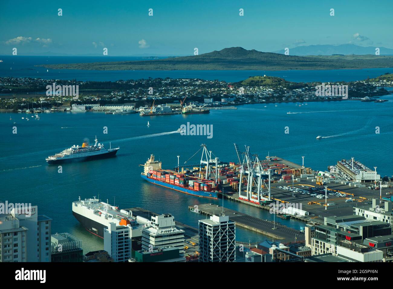 Ein Blick über den Hafen von Auckland mit einem kleinen Schiff, das absegelt, vom Sky Tower mit Schiffsliegeplätzen im Vordergrund. Auckland, Neuseeland Stockfoto