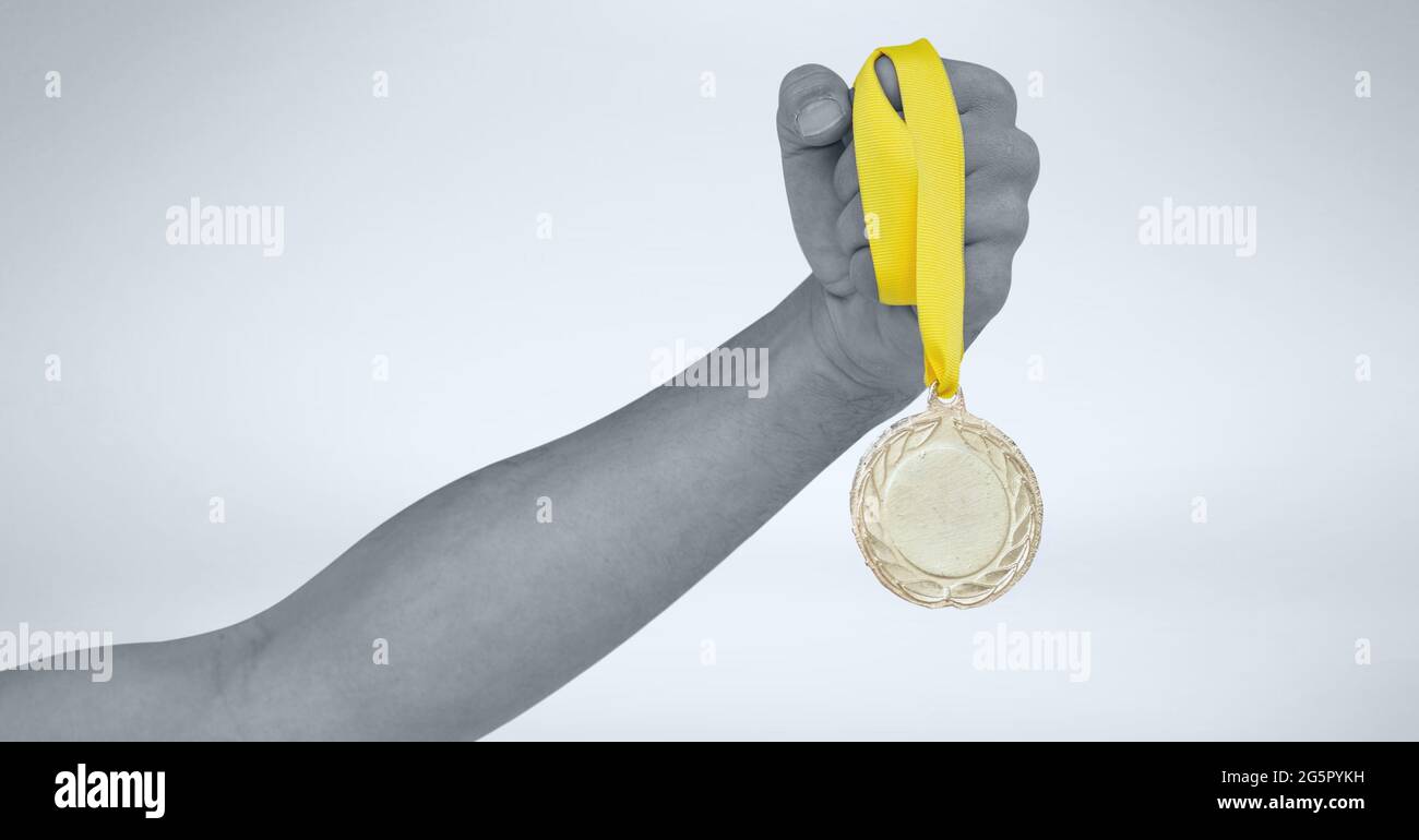 Schwarz-weißes Bild einer Hand mit einer Medaille vor grauem Hintergrund Stockfoto