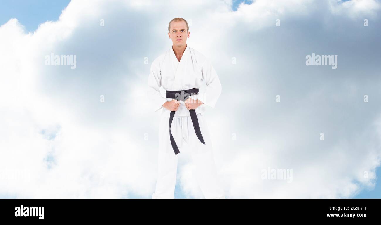Porträt eines kaukasischen männlichen Kampfkünstlers mit schwarzem Gürtel gegen Wolken am blauen Himmel Stockfoto