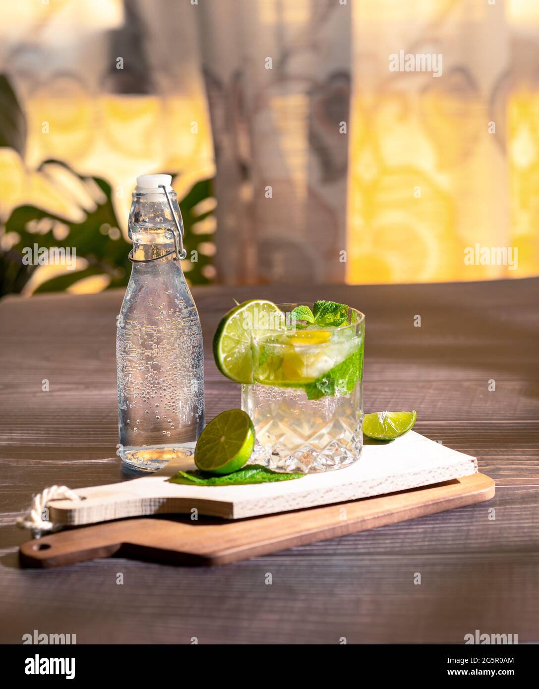 Helle Fotografie eines kalten Getränks, eines Glases Mojito mit Minzblatt, Eis, Zitrone und Zucker auf einem Holztisch im Retro-Stil Stockfoto